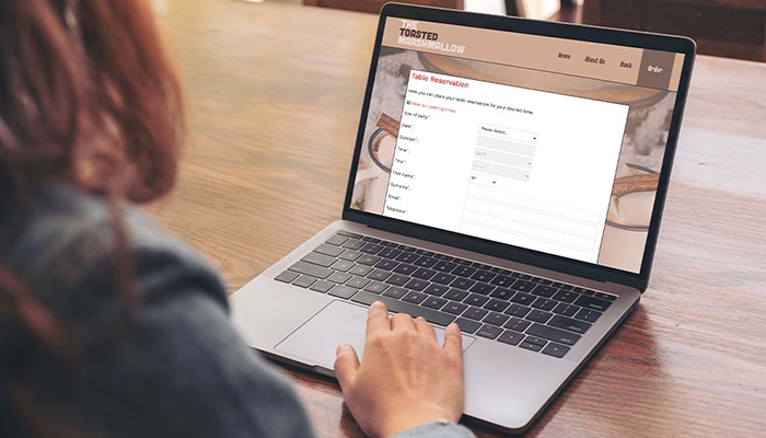 Woman using laptop on table with TouchReservation software by ICRTouch