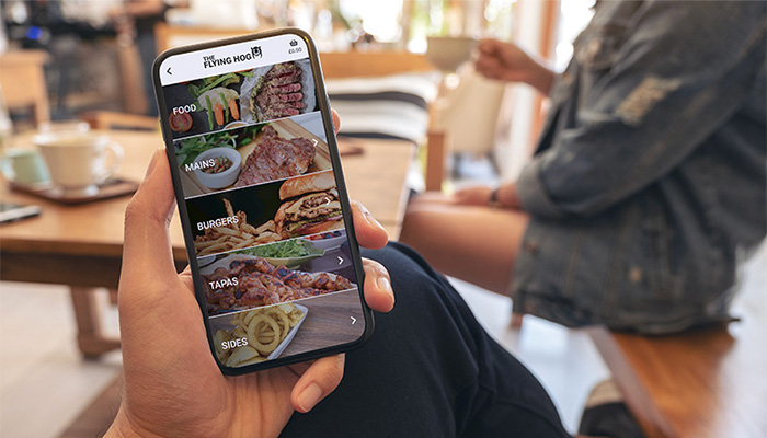 Women sat in cafe holding phone with screen showing ByTable menu