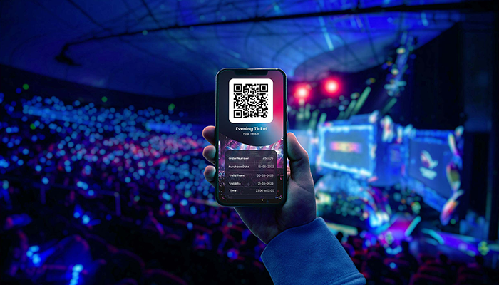 Person holding phone with digital ticket on, at a concert